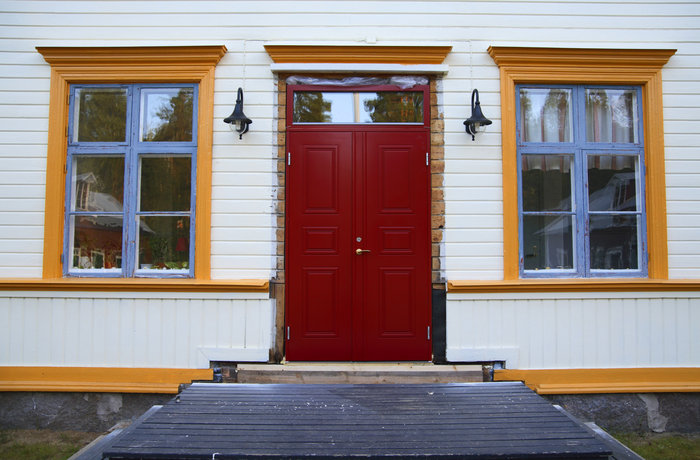 Röd ytterdörr på vitt hus.