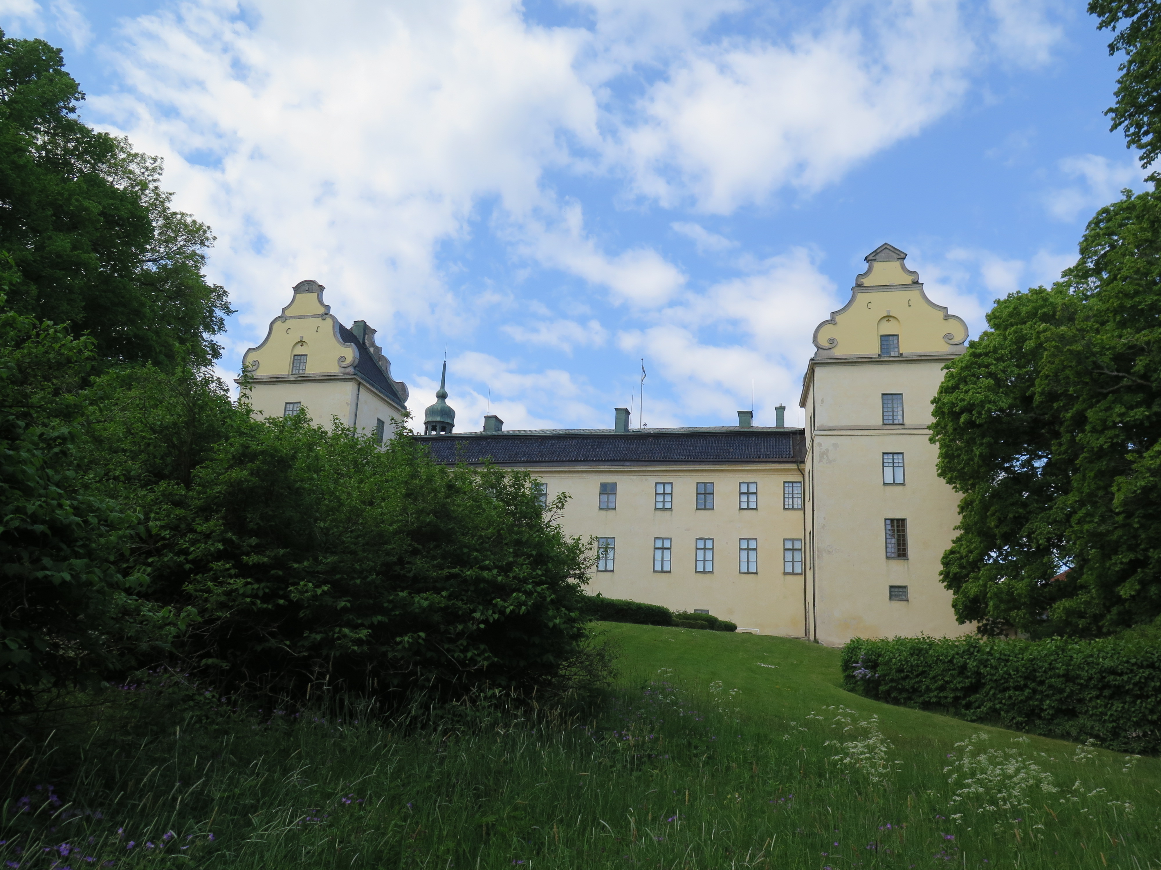 Tyresö slott frön sjösidan, gul fasad i lummig parkmiljö