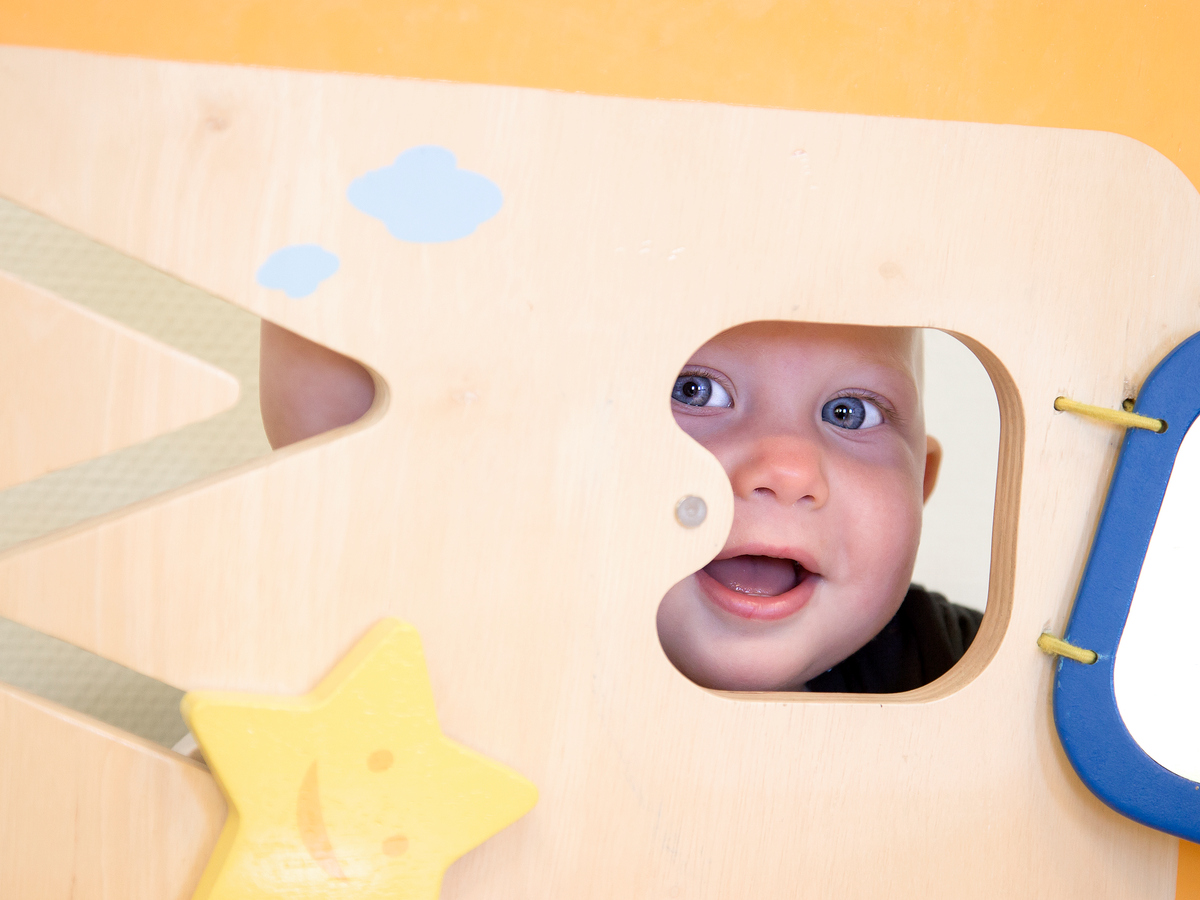 Litet barn tittar ut genom hål i leksak