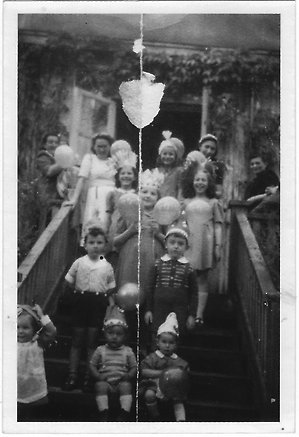 Barn på trappa, iförda pappershattar och med ballonger.