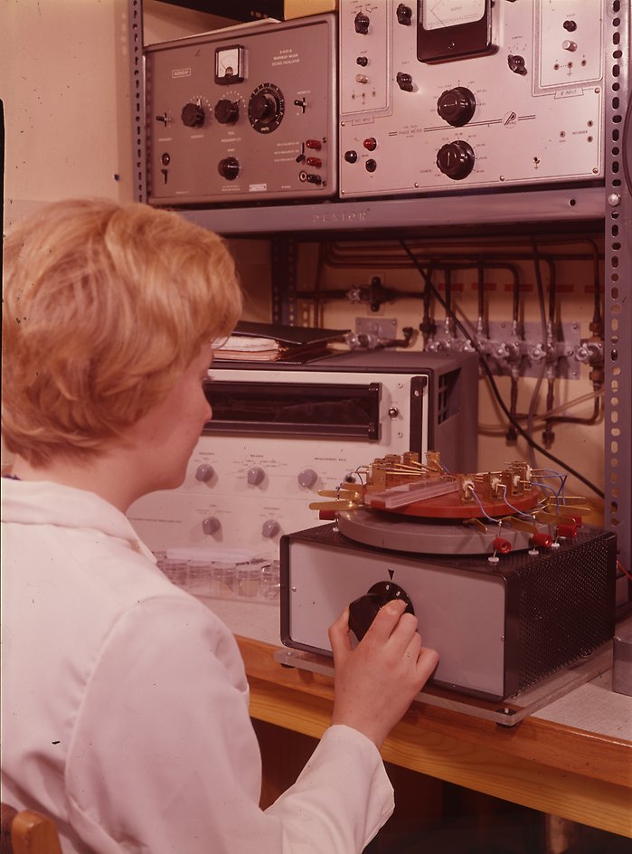 Ljushårig kvinna vid avancerade tekniska apparater från 1970-talet